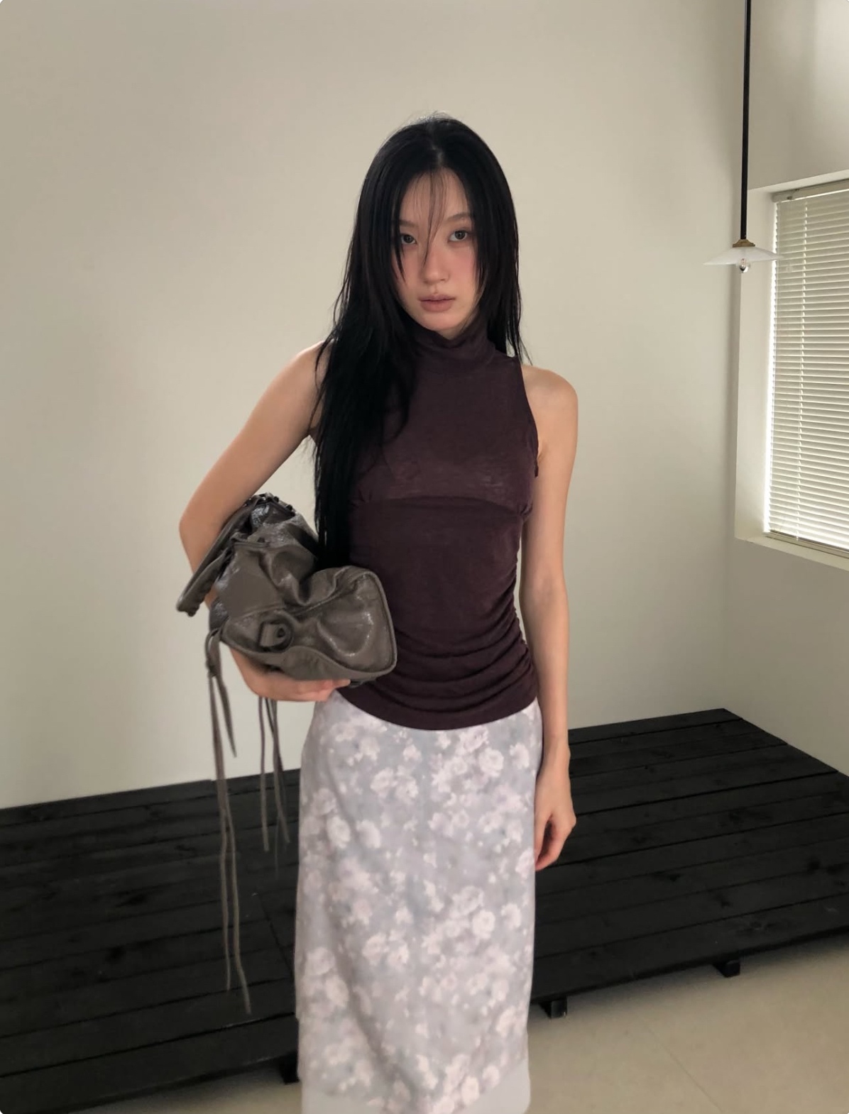 設計亮點在於優雅高領（Turtleneck/High Neck）搭配側邊抓皺（Side Ruched/Gathered Detail）與胸下弧形車縫線（Underbust Seam），加上輕薄微透的質感羊毛混紡面料，兼具保暖度與輕盈修身效果。
