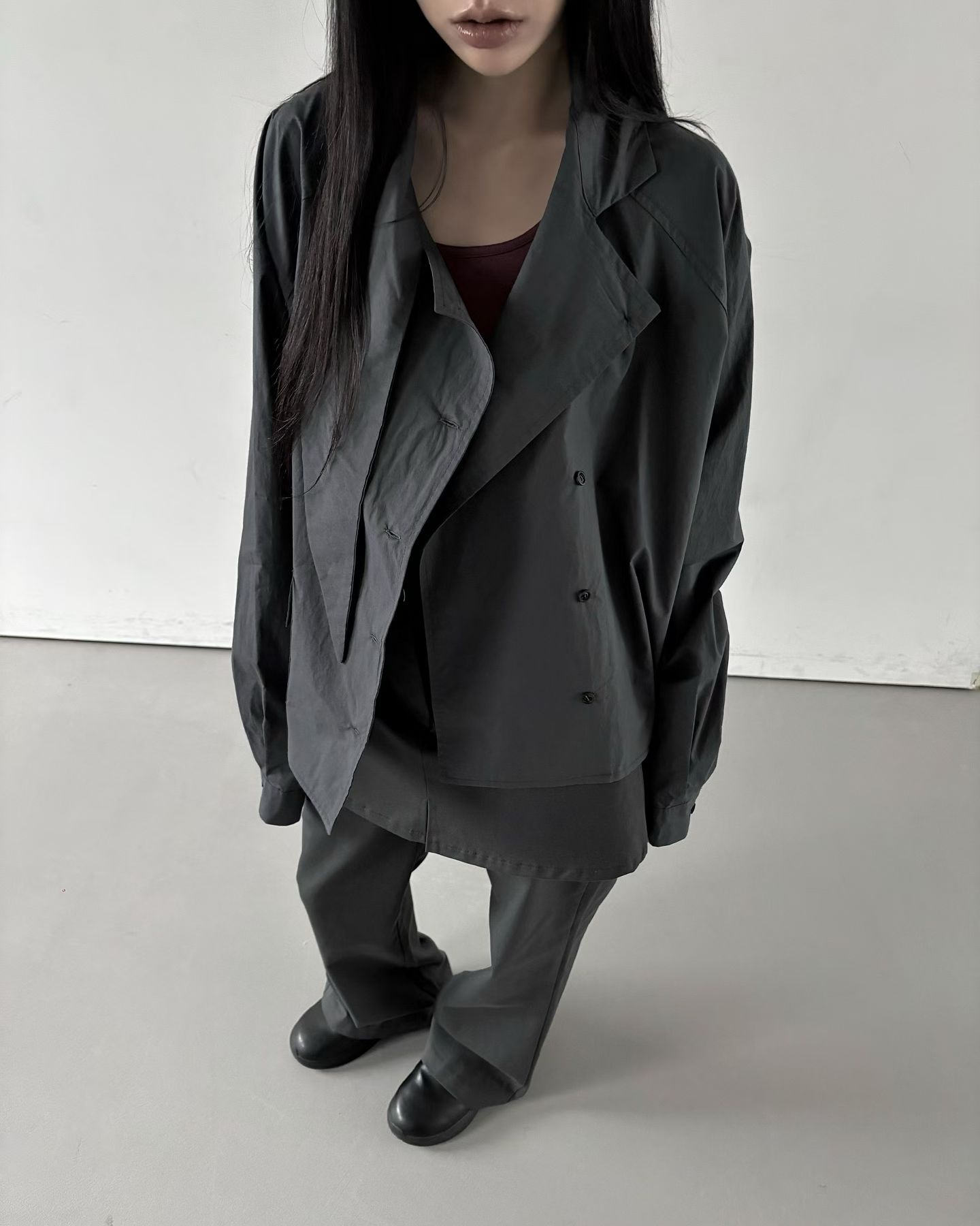 全扣時呈挺括的高領防風廓形，解開時則能展現隨性的大翻領或多層次襟片，搭配插肩袖與前口袋細節，既俐落又有型。
